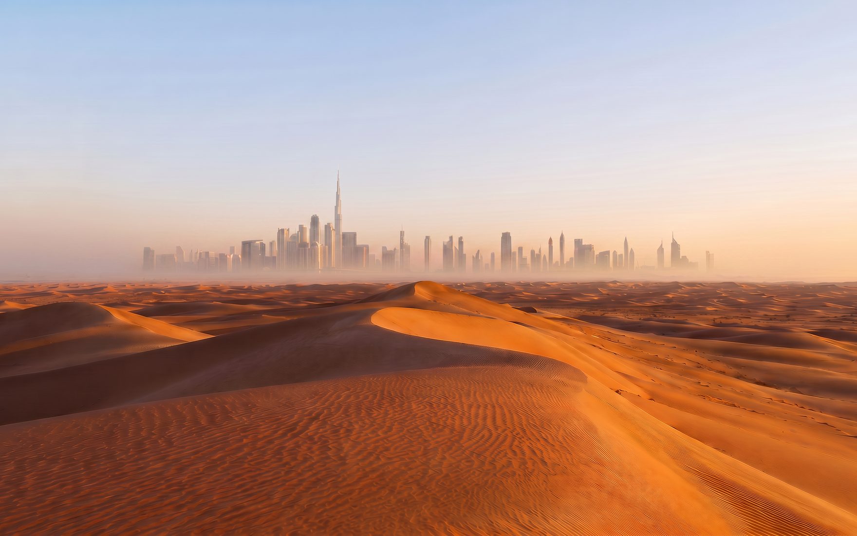 The Dubai skyline rising beyond the dunes at first light